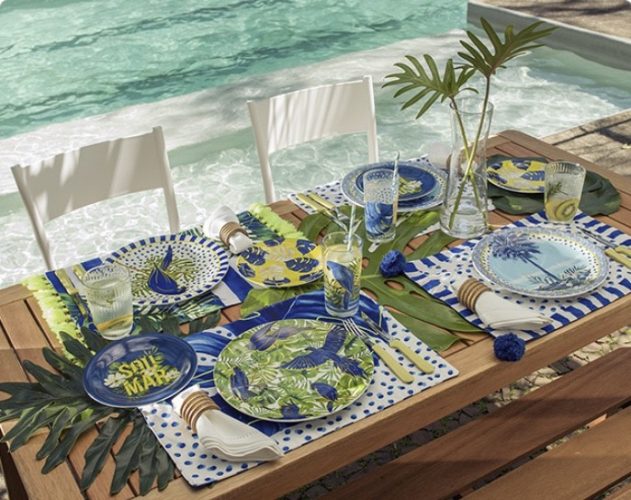 mesa posta na beira da piscina , com pratos coloridos e copos pintados, da marca Farm