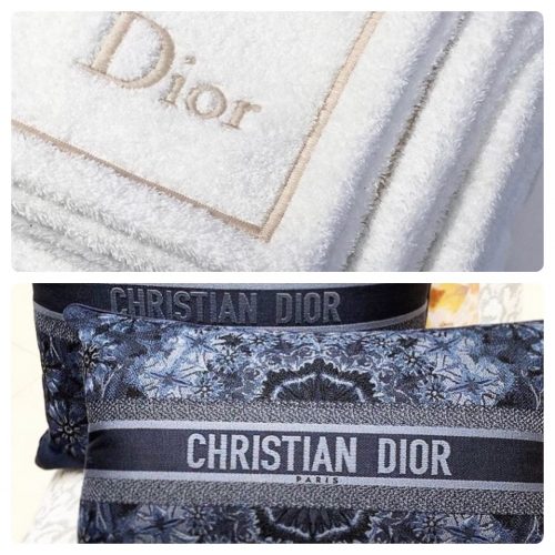 Toalha branca e almofadas azuis da com a marca Dior escrita
