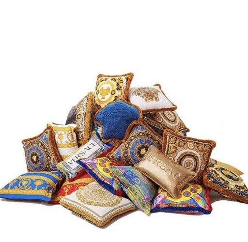 Pilha de almofadas douradas e azul da grife Versace.