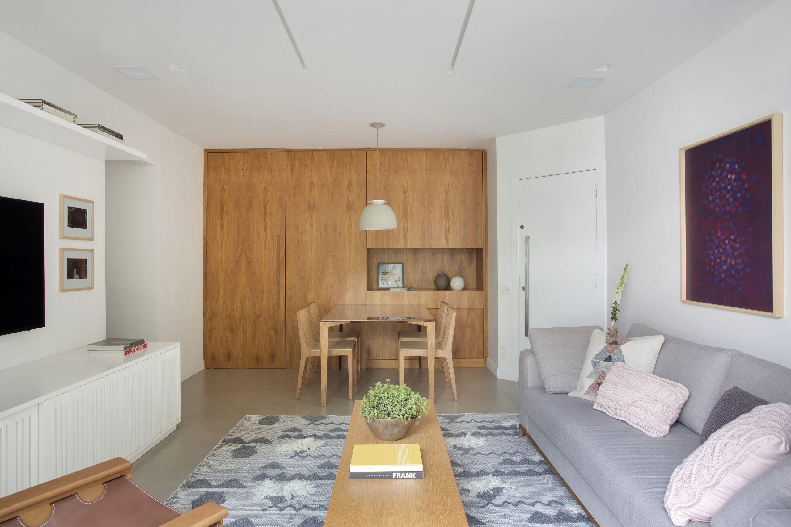 Pequenas interferências para tornar os ambientes mais amplos em um apartamento no Leblon. Funda da parede da mesa de jantar com painel em madeira 