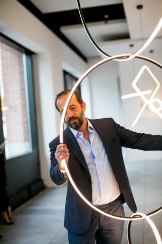 Michael Anastassiades, Designer do ano da Maison Objet. Foto do design segurando um circulo iluminado