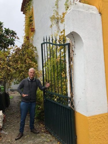foto do arquiteto Maurico Nóbrega em Portugal, no portão de ferro em uma casa.