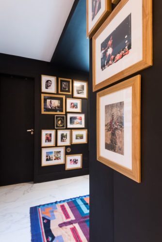 Corredor e portas pintado de preto abrigam coleção de quadros com a moldura em madeira