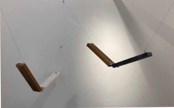 Foto de uma exposição de artes plasticas, dois pedaços de madeira cortados ao meio pendurados