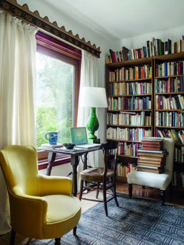 como enxergam a quarentena os principais fotógrafos de arquitetura do mundo. Foto com uma estante de livro, em frente a janela, uma escrivaninha com uma cadeira e um abajur verde. 