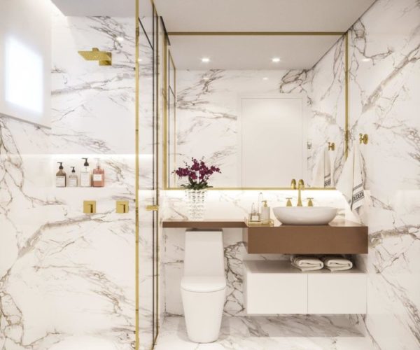 Sofisticação em apartamento com 100m². Banheiro todo revestido em mármore branco com veios marrons e detalhes dourados