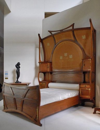 Cama Art Nouveu. Fonte: Museu d'Orsay. Cama em madeira com cabeceira muito alta e mesinhas laterais acopladas