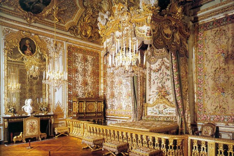 Quarto da Rainha Maria Antonieta na Palácio de Versalhes. Paredes revestidas de tecido floral e dossel em cima da cama