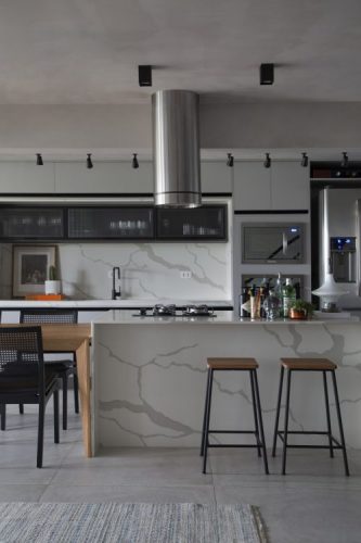 Cozinha com estilo. Essa cozinha totalmente integrada para a sala com ilha central em porcelanato imitando mármore e ao lado uma mesa de madeira