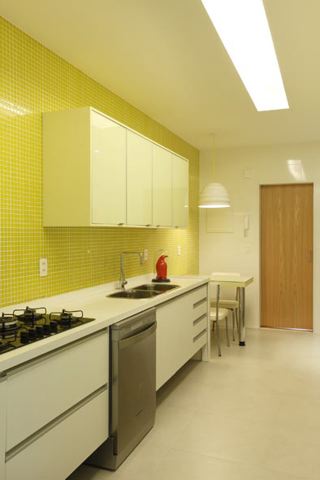 Cozinha com estilo. Cozinha bem iluminada, paredes revestidas de pastilhas amarelas e bancada e armários brancos