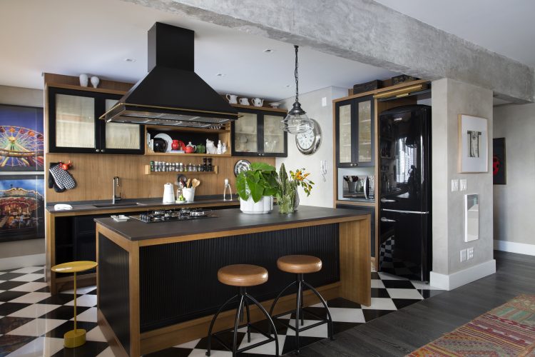 Cozinha, muito prazer. Cozinha integrada a sala, totalmente aberta. O piso xadrez de preto e branco delimita a área da cozinha, com ilha em pedra preta e coifa tb preta. 