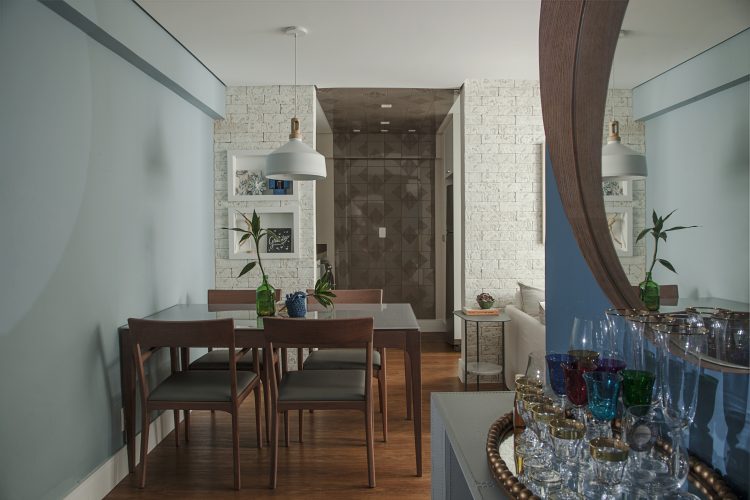 Apartamento de 40 m² com soluções para sua pequena metragem. Sala com a mesa de jantar em madeira enconstada na parede pintada de azul