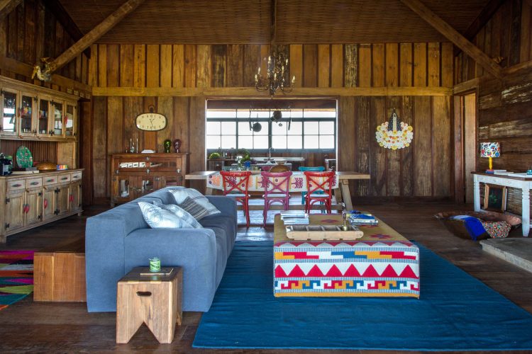 Interiore de uma Casa de campo toda em madeira de demolição. Decorada com sofá azul e puff estampado