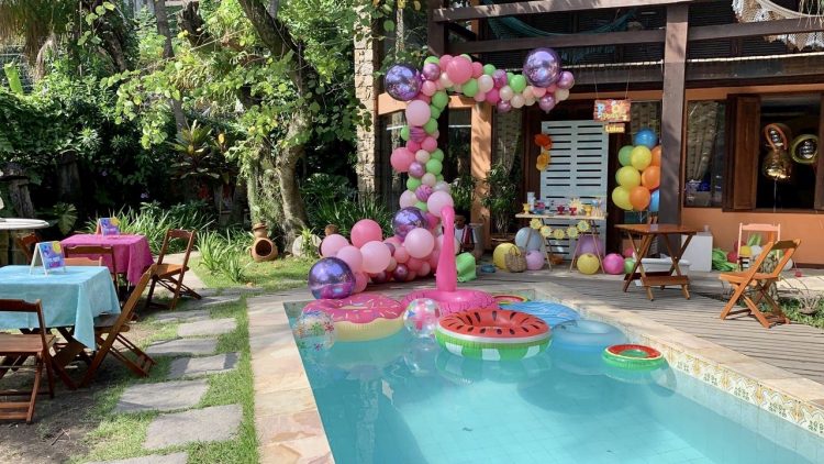No jardim de uma casa, bolas coloridas, boias de flamingo na piscina