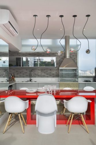 Na Cobertura duplex, em Icaraí, Niterói. No andar de cima, area gourmet com churrasqueira, mesa vermelha e cadeiras brancas