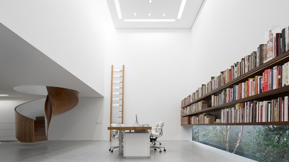 Lúdica e funcional, a magia das escadas helicoidais. Escada escultural em madeira dentro de um cubo branco, uma sala com pe direito alto