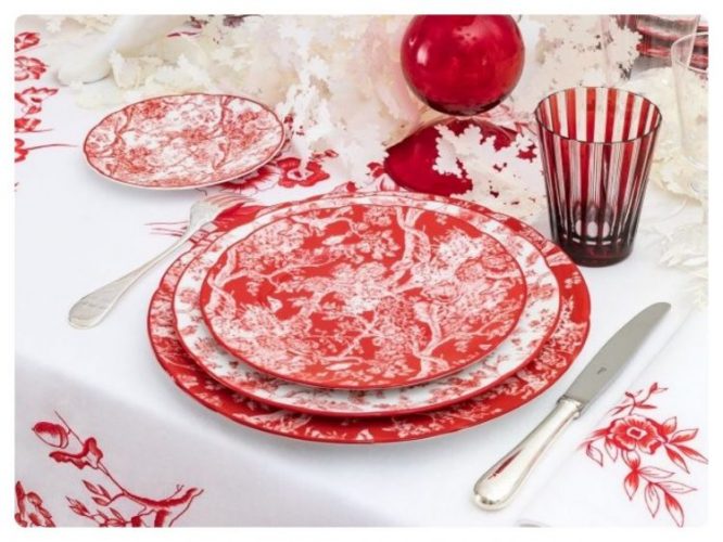 Estampa Toile de Jouy na louça da linha Dior Home na cor vermelha. Mesa com toalha branca e pratos e copos na cor vermelha