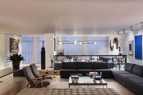 Projeto contemporâneo em apartamento dos anos 70 em São Paulo. Sala ampla, com piso em madeira. Doi sofás formando um L 