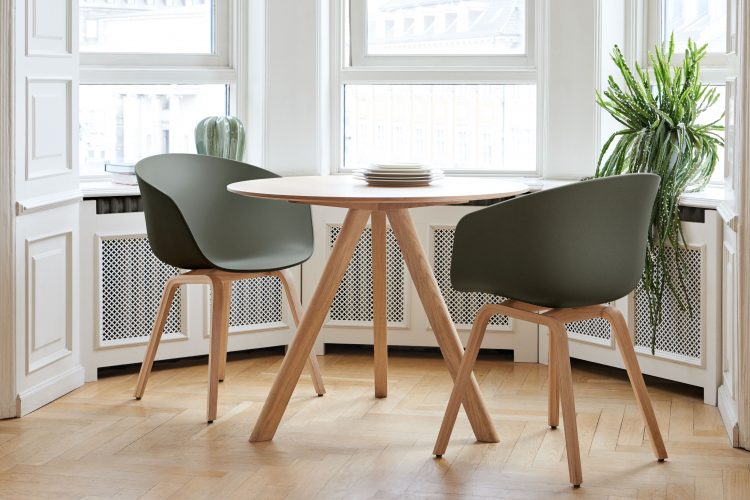 mesa redonda com duas cadeiras pretas com pés em madeira