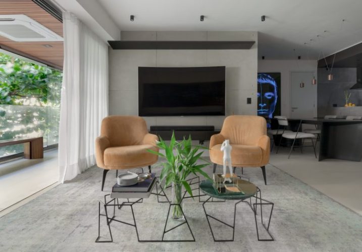 Apartamento no Leblon com décor minimalista e brutalista. Tapete cinza , paredes em concreto, mesa de centro em ferro e tv na parede