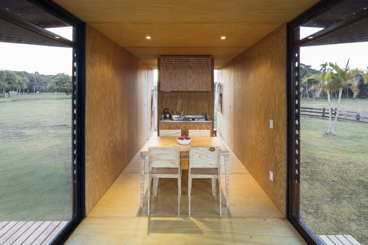  sistemas pré-fabricados. Interior de uma casa pré fabricada. Estreita, todo forrado de madeira e uma mesa no meio