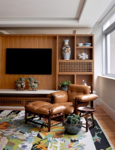 seleção de 10 cadeiras icônicas do design, Poltrona Mole. Poltrona em couro e madeira em uma sala de tv com painel em madeira
