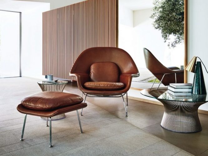 seleção de 10 cadeiras icônicas do design, WOMB .Poltrona em couro marrom com puff na frete em um ambinete claro de uma sala so com ela 