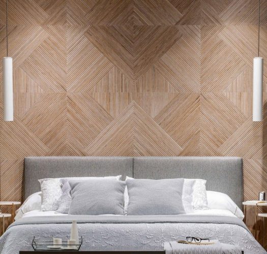 Parede ao funda da cama, com cabeceira cinza, revestida de porcelanato imitando madeira criando desenhos geometricos
