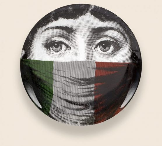 Prato de porcelana da marca Fornasetti com um rosto estampado a e boca coberta com a bandeira da Italia