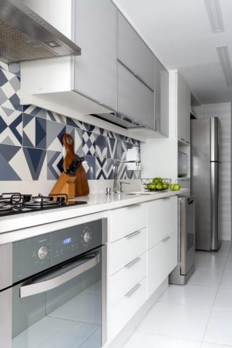 cozinha tipo corredor , com aramarios brancos e no frontão azulejos graficos azuis