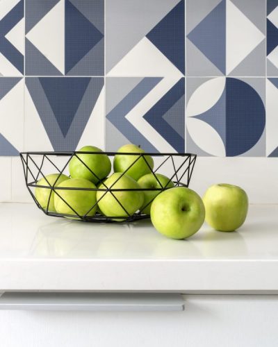 Bancada branca, cesto de fritas com maçã verde e azulejos azuis na parede