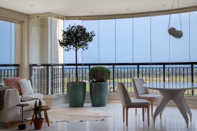 Apartamento de 300 m2 com décor contemporâneo. Varanda fechada com paineis em vidro e decoração como uma sala de estar; Sofá, mesa redonda e vasos