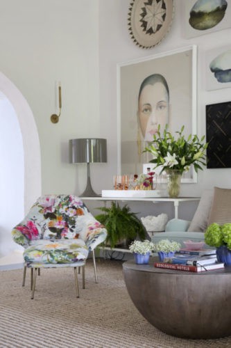 Poltrona floroda. parede com quadro grande e mesa com flores