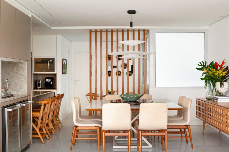 Cozinha integrada a área social, aberta para a sala de jantar com mesa quadrada e apinel em madeira ripado atras