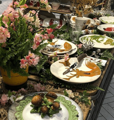 Mesa posta na loja francesa Au Bain Marie. Pratos com estampa de um alçe pintado e flores enfeitando a mesa