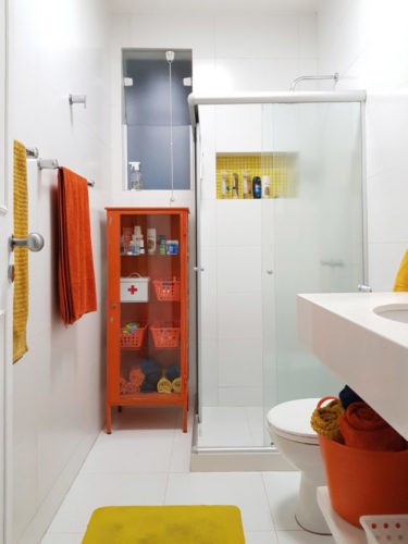 Banheiro todo branco com movel na cor laranja