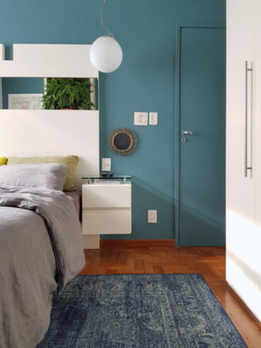Quarto com parede e pota pintado de azul claro, piso em madeira com paginação espinhe de peixe e tapte azul
