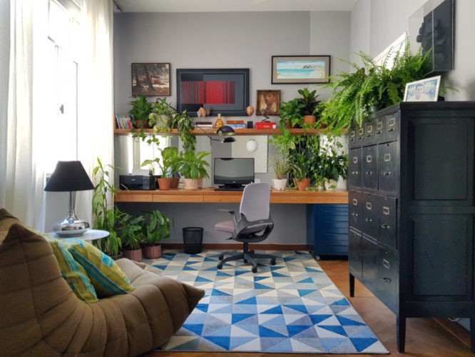 Home office repleto plantas , no melhor estilo Urban Jungle. Bancada em madeira, tapete azul e movel alto com gaveteiro