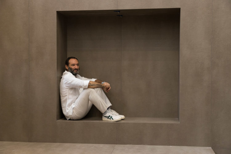 designer Marcelo Rosenbaum, sentado vestindo roupa branca