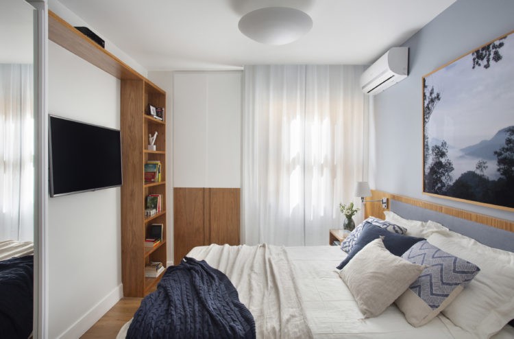 Quarto com cama de casal, tv na parede em frente a cama e ao lado armario em madeira