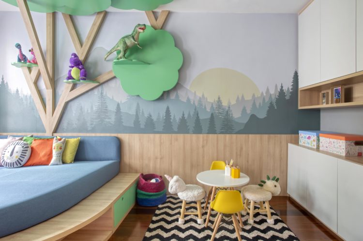 Rancho da família inspira brinquedoteca dos netos. Papel de paede de floresta, meia parede com lambri em madeira e uma arvore tb em madeira instalada na parede.