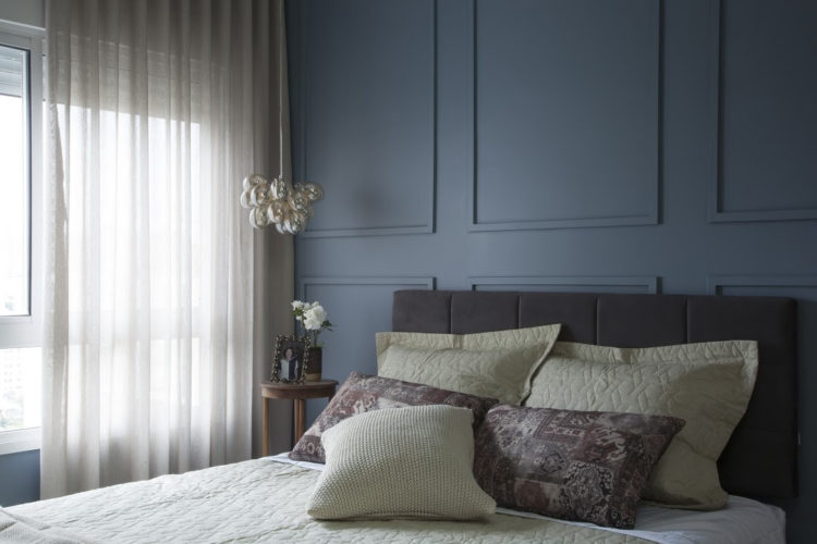 Boiserie: 5 dicas de arquitetos para usar esse elemento no décor, Quarto de casal com a parede atras da cama pintada de azul e com boiserie ( molduras finas) na mesma cor aplicada.