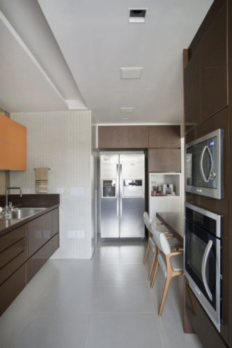 Cozinha com planta em corredor, armarios na cor marrom e apenas um superior com as portas na cor laranja