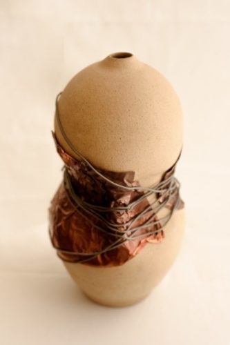 Vaso de cerâmica com um arame no meio para fazer alusõa ao crpo feminino usando espartilho.