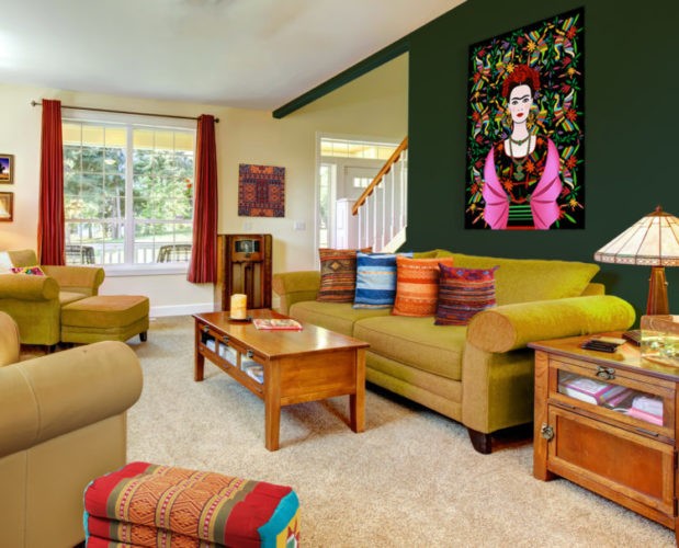 Parede amarelinho claro no fundo, na frente parede verde. Sala bem colorida, sofá amarelo e almofadas laranja