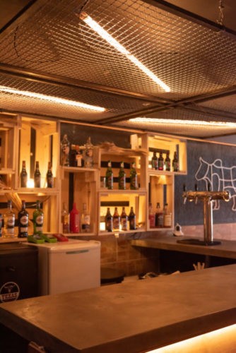 No bar da hamburgueria, caixotes de madeira com cervejas decoram o ambiente