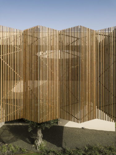 Ripas de madeira natural e colocadas na diagonal revestem a fachada da casa