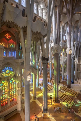 Lado de dentro do Templo Expiatório da Sagrada Família, colunas altas, vitrais 