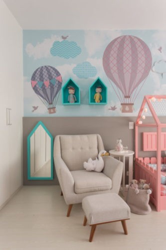 Papel de parede do quarto de beb~e com balões e na frente uma oltroba bege com puff