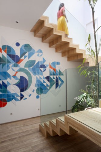Escada em madeira, ligando dois andares da cobertura e na parede um painel de azulejos